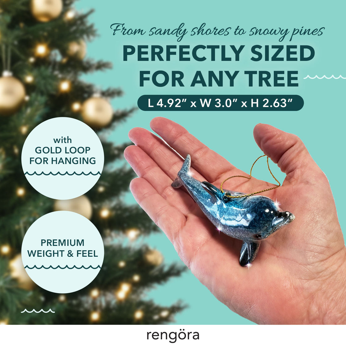 A hand holds a sparkly blue dolphin Christmas ornament in front of a glowing tree.