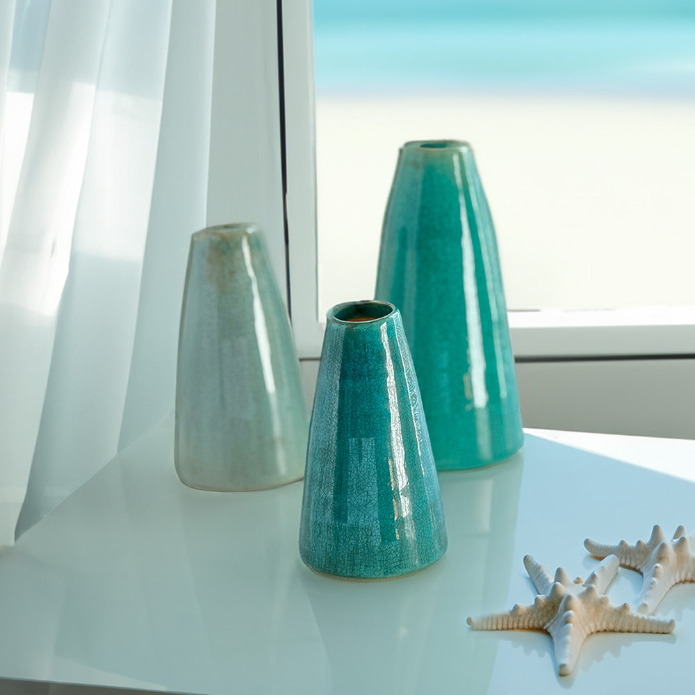 A captivating set of three unique artisanal vases, complemented by a dried starfish on the table in front of the window