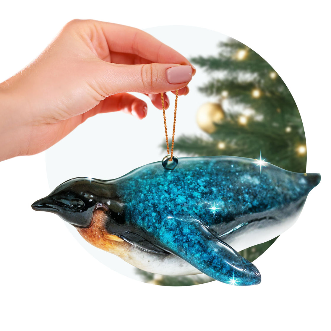rengöra penguine ornament held by a hand with a golden string, against the blurred backdrop of a decorated Christmas tree