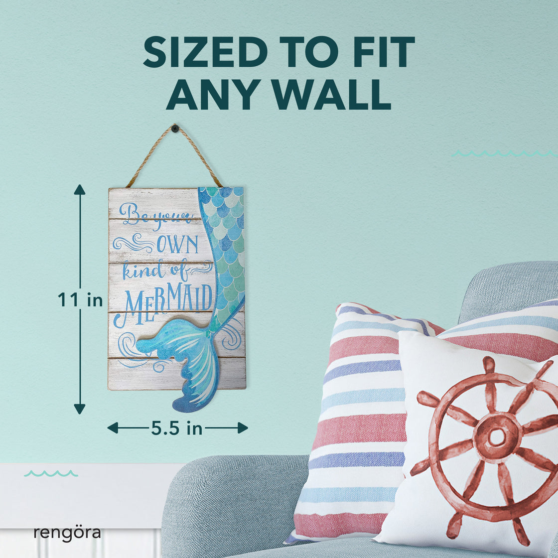 Mermaid plaque hung on a soft blue wall, shown above a coastal-themed pillow and labeled with dimensions 11 inches tall by 5.5 inches wide and text “Sized to Fit Any Wall.