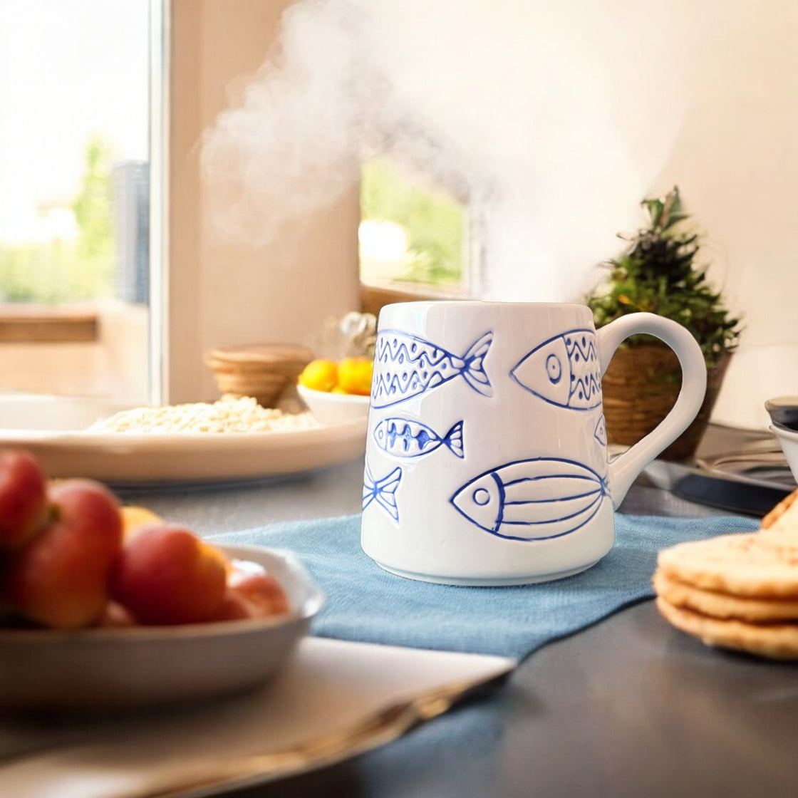 Steaming ceramic rengöra fish mug on a breakfast table surrounded by fruit and flatbreads — a cozy morning scene in a sunlit kitchen.