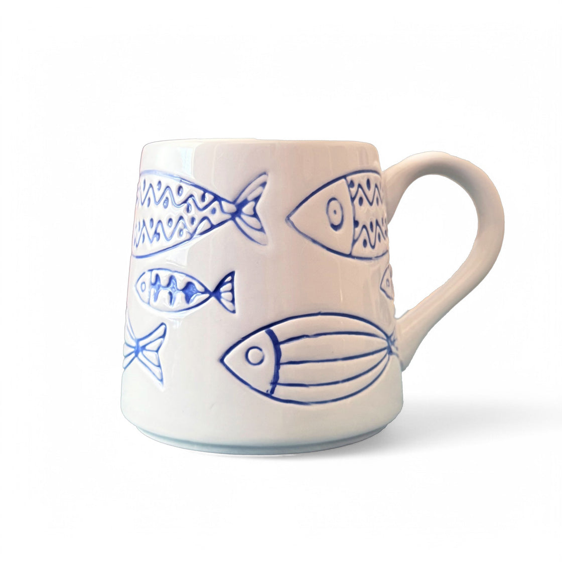 Close-up of a rengöra ceramic mug with blue fish design on a clean white background — product showcase of minimalist, ocean-inspired drinkware