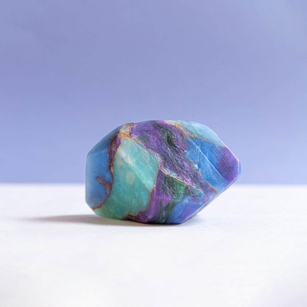 An up-close view of a purple crystal soap, mirroring the appearance of a genuine crystal, set against a simple white backdrop
