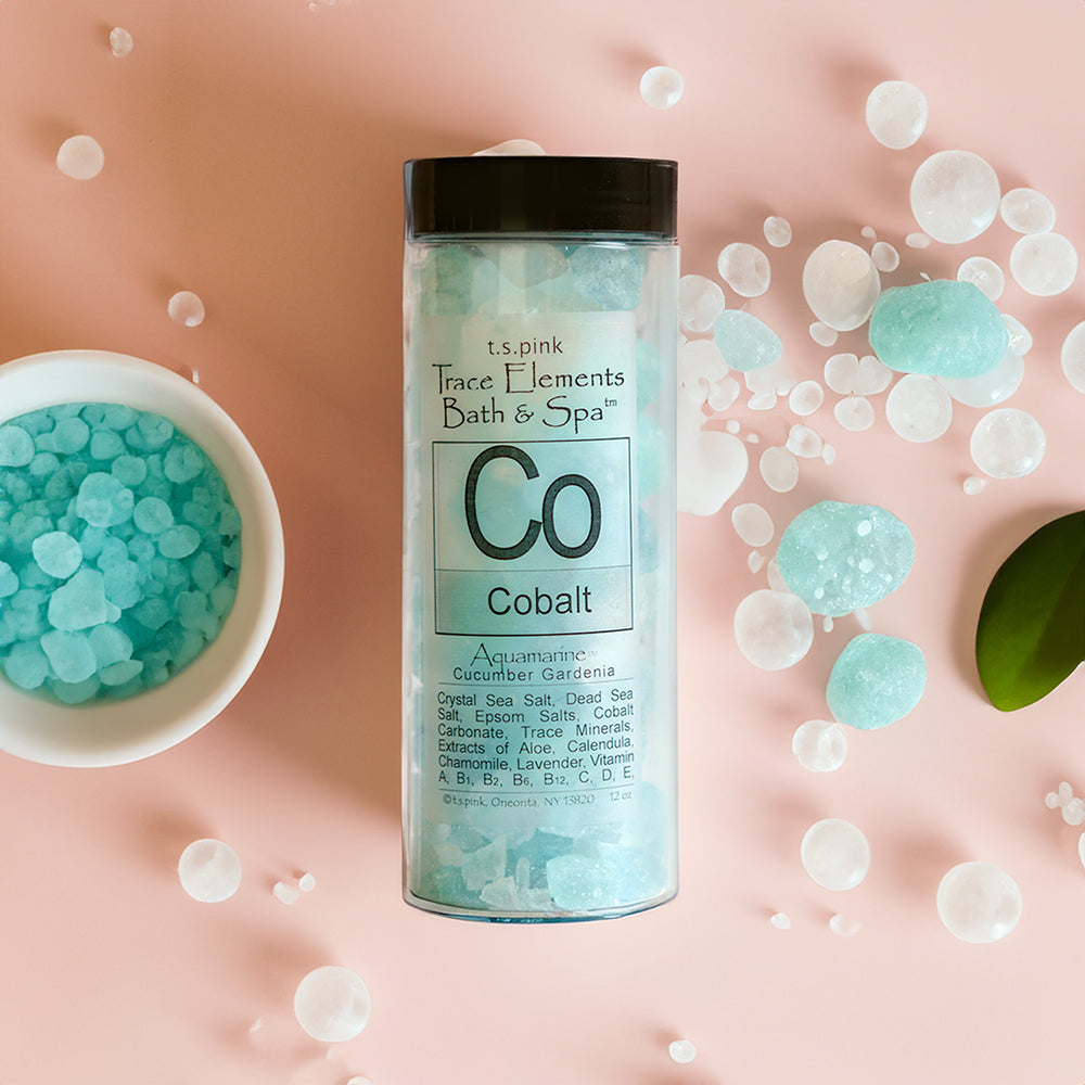 Flat lay view of Cobalt bath salts - clear cylindrical package shown with salts laying around it on a peach colored background