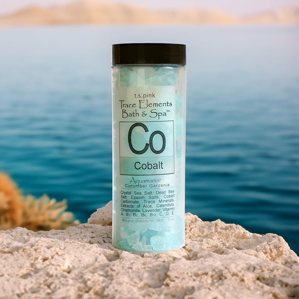 Trace Elements Bath + Spa Cobalt Bath Crystals shown sitting on a rock with a beautiful lake or ocean background behind them.