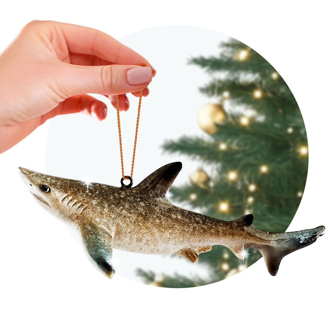 rengöra shark ornament held by a hand with a golden string, against the blurred backdrop of a decorated Christmas tree