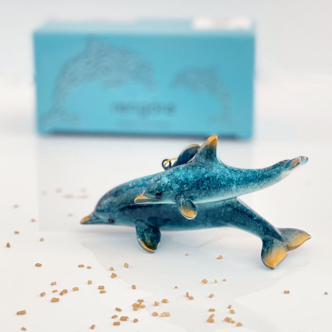 rengöra blue dolphin Christmas ornament (mother and calf) with blurred image of blue packaging box in the background