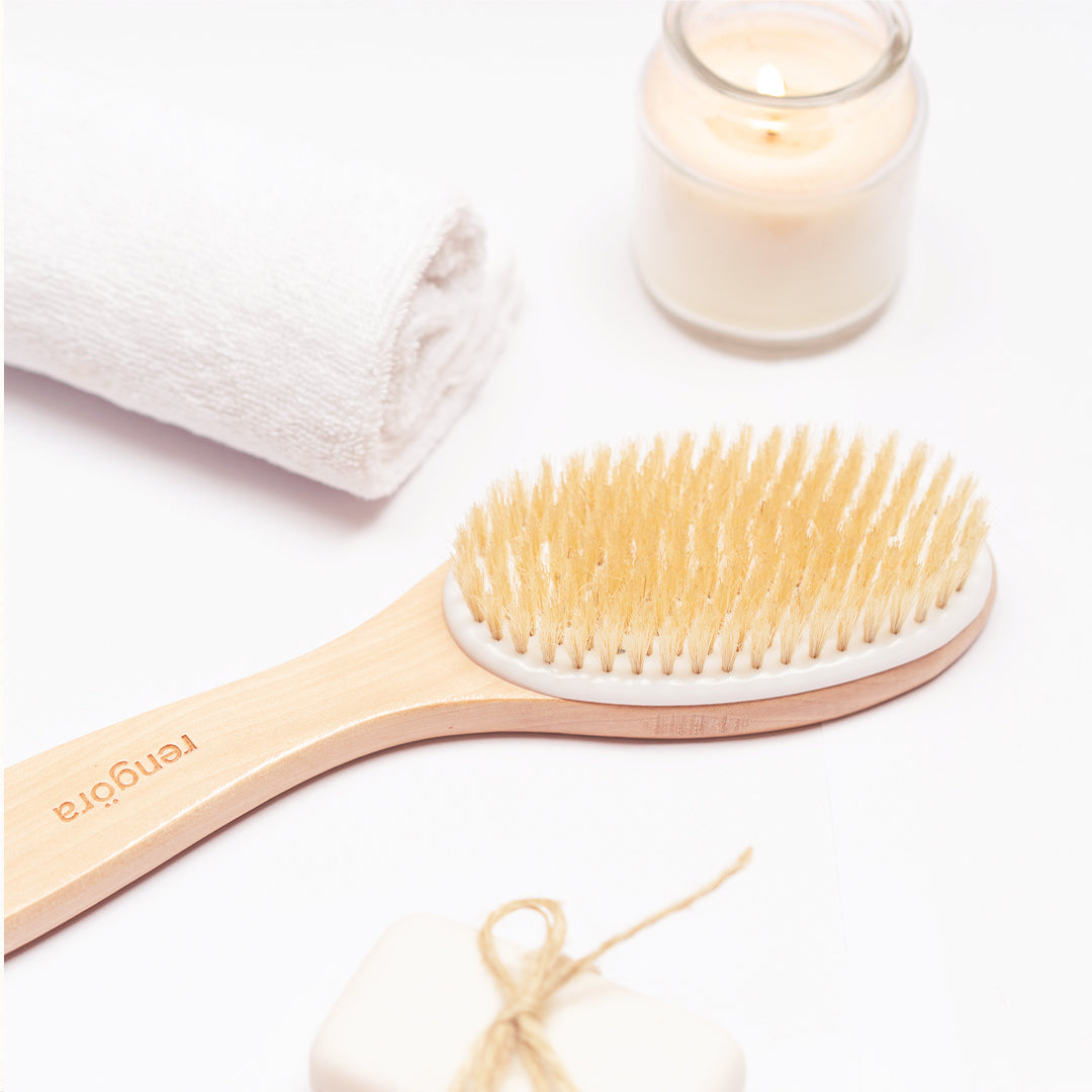 rengora's ergonomic handled dry skin brush with white towel and white candle in background