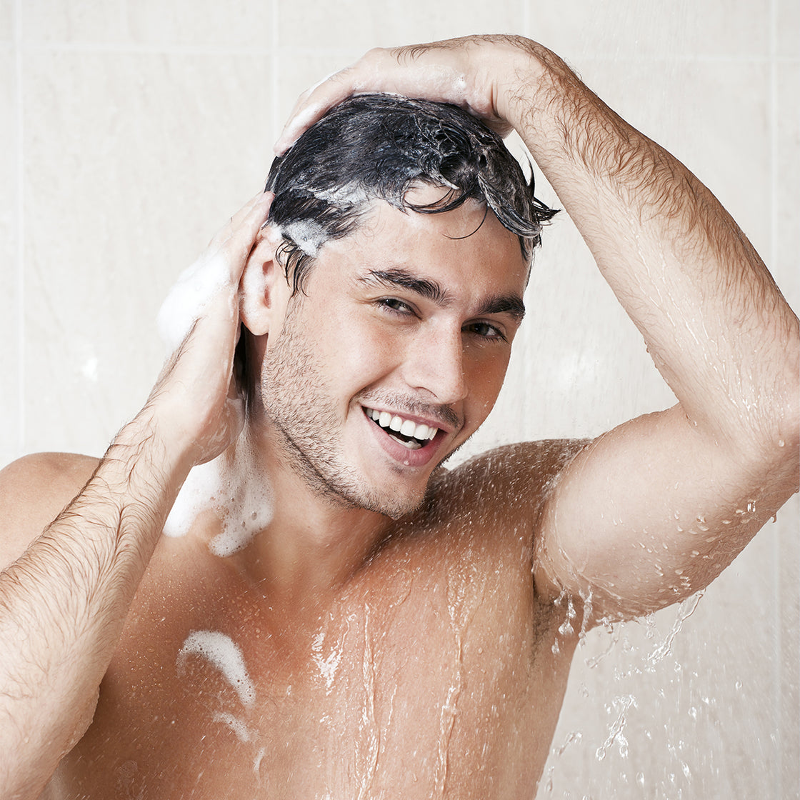 happy man washing his hair in the shower
