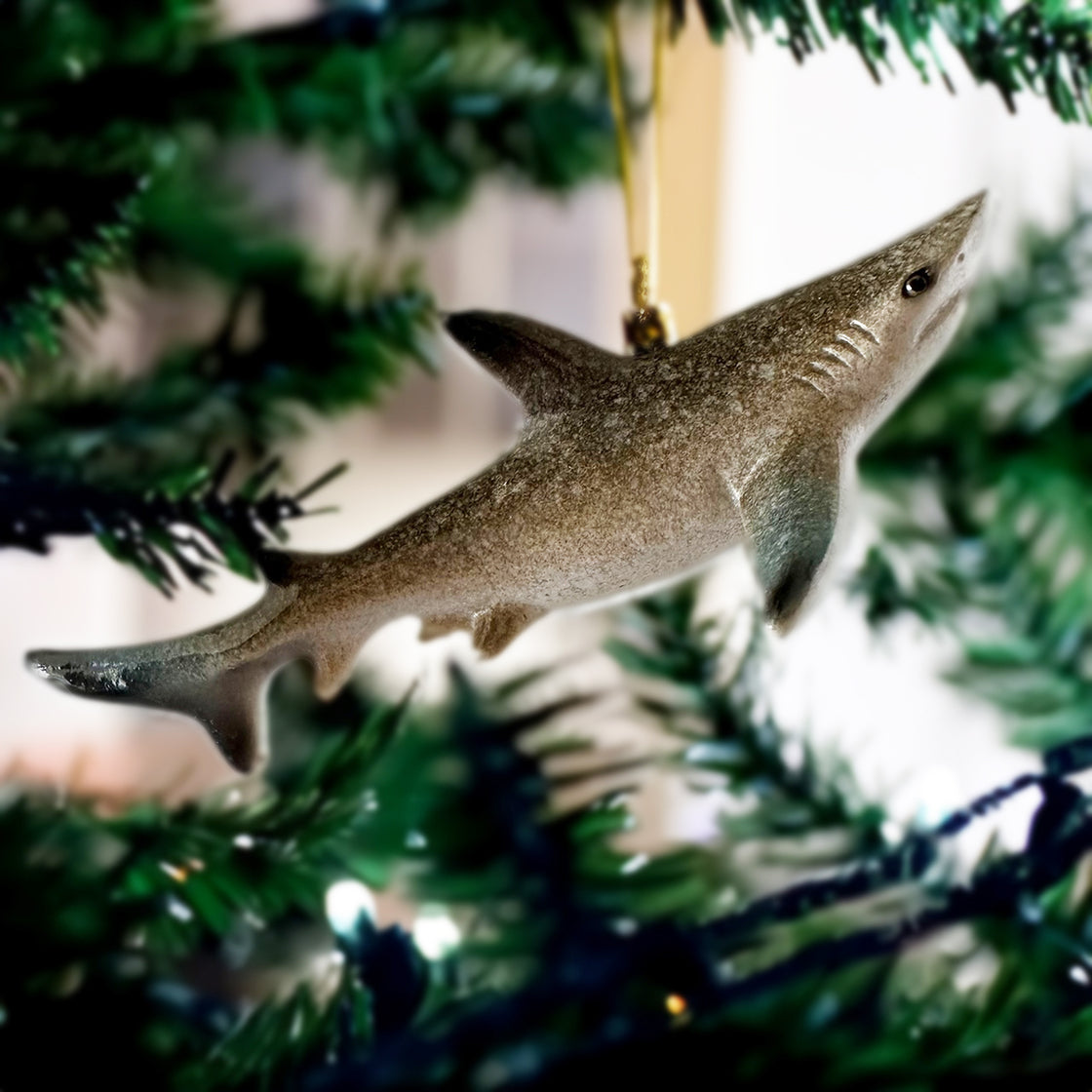 A rengöra shark ornament suspended from a Christmas tree, captured from a side angle, with a gently blurred background