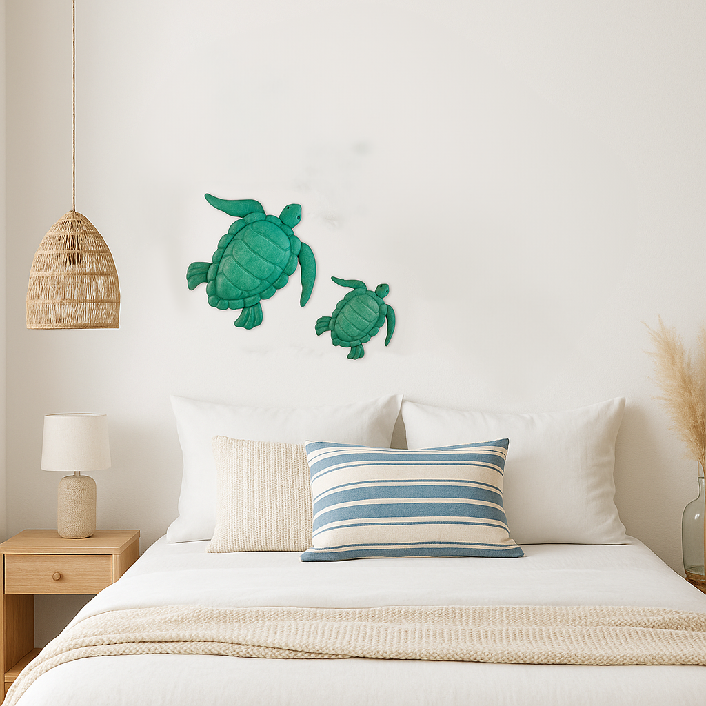 Enameled metal sea turtle wall art set displayed above a coastal-style bed with neutral and blue striped decor