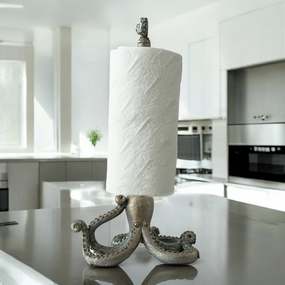 Octopus paper towel holder in full use, supporting a paper towel roll on a kitchen counter with clean white cabinetry in the background.