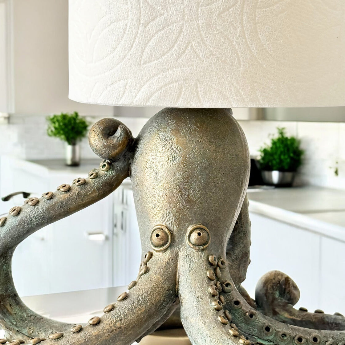 Close-up of the octopus head and curling tentacles, supporting a roll of paper towels in a bright kitchen setting.