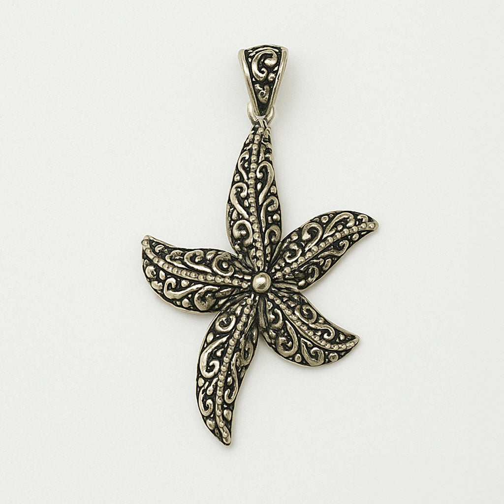 A detailed silver pendant in the shape of a starfish, featuring ornate scrollwork on each arm, photographed on a white background for a clean, minimalistic product display.