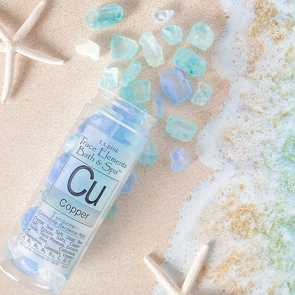 Rengöra Bath salts in the shade of blue scattered across the sandy beach.