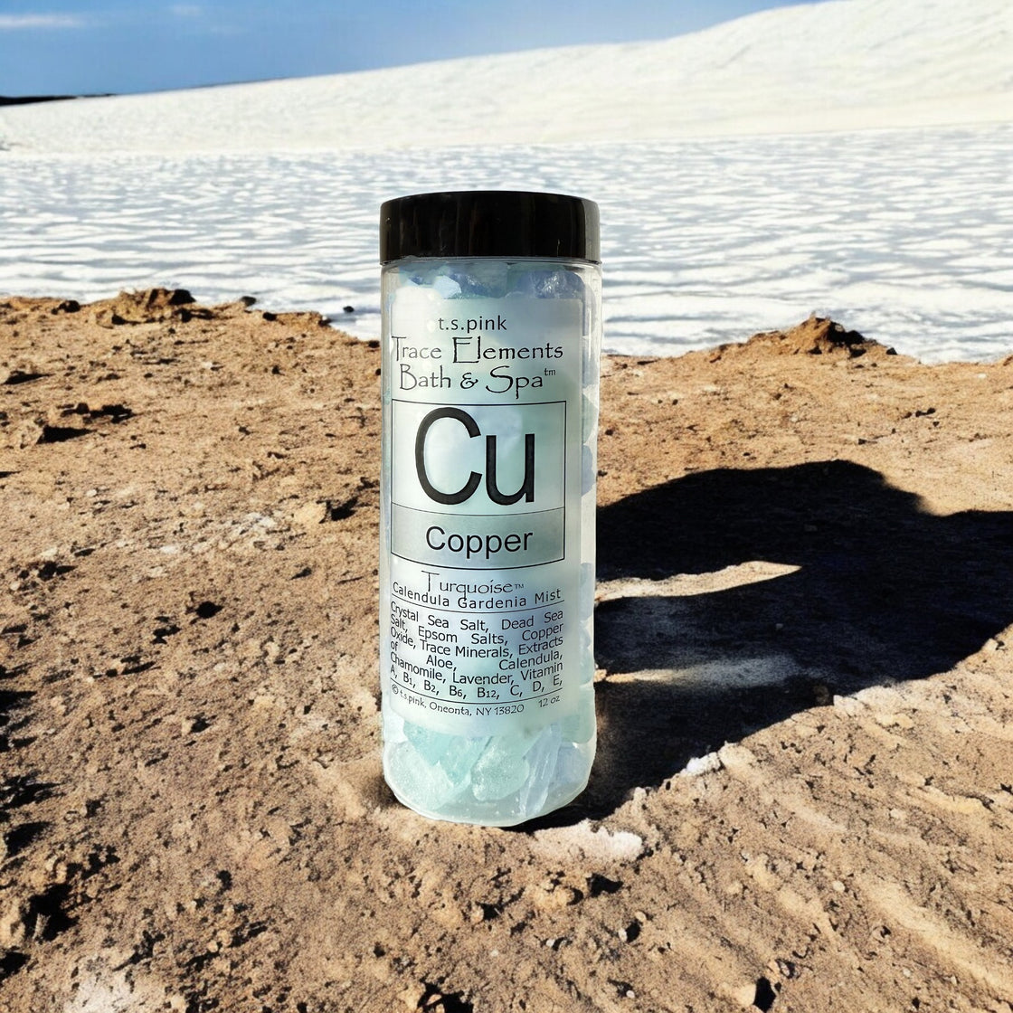 A clear plastic jar with a black lid, filled with Rengöra copper-infused bath salts, stands amid towering white salt mountains.