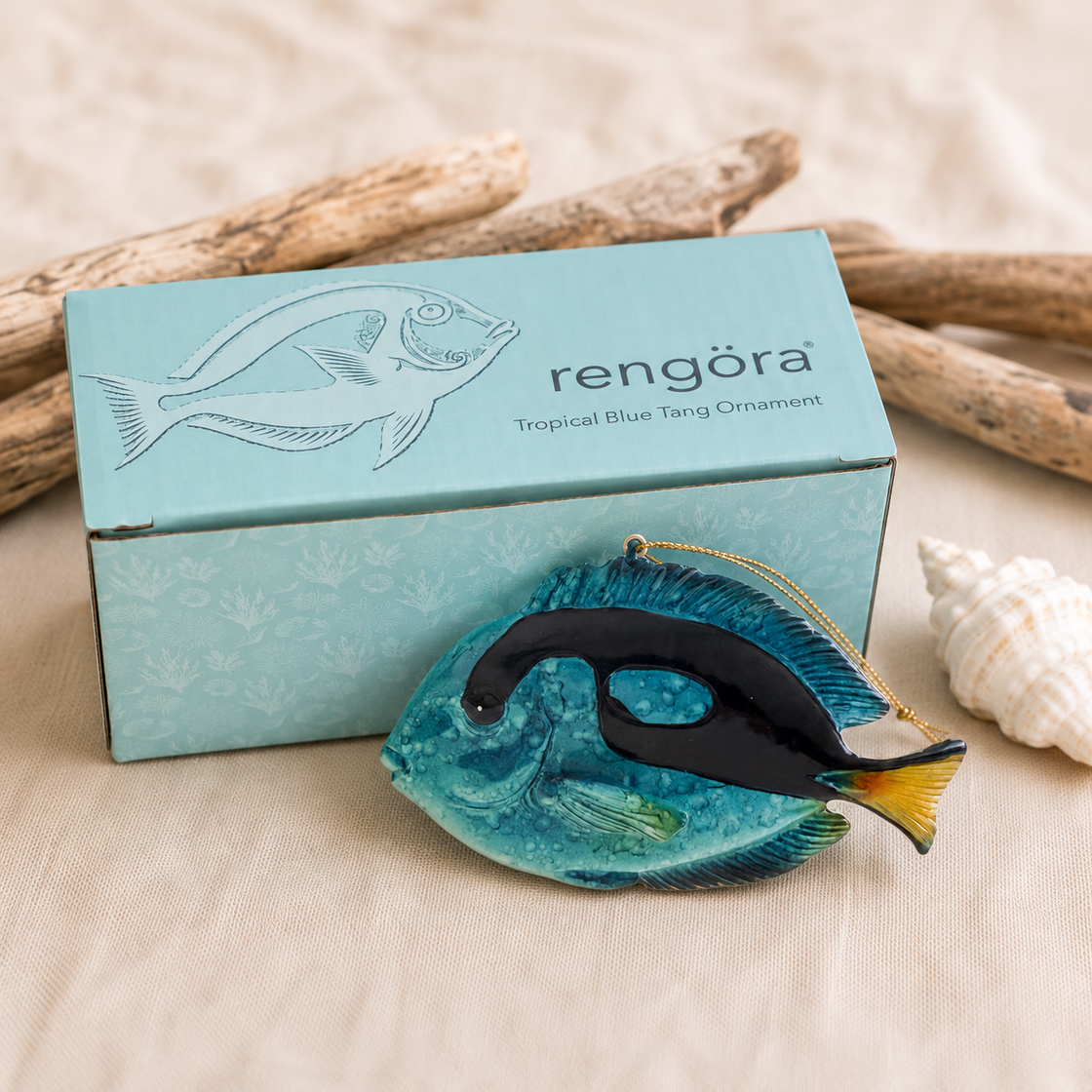 Rengöra tropical blue tang ornament displayed beside its aqua gift-ready box with driftwood and coastal accents.