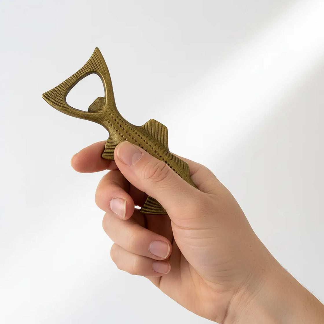Hand holding a bottle opener against a white background