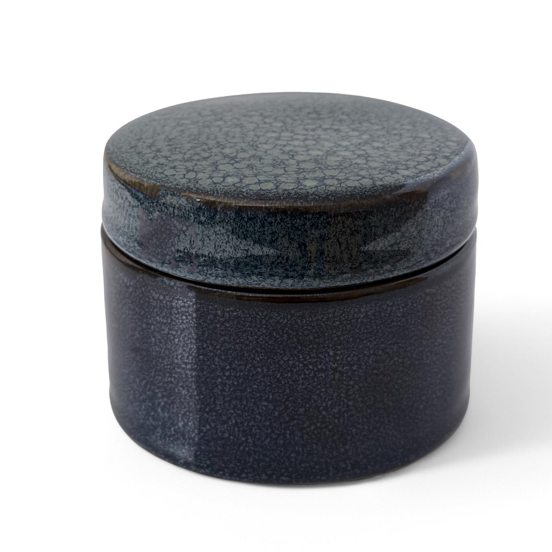 Elegant handmade navy ceramic storage dish with lid showing detailed speckled glaze on a crisp white background.