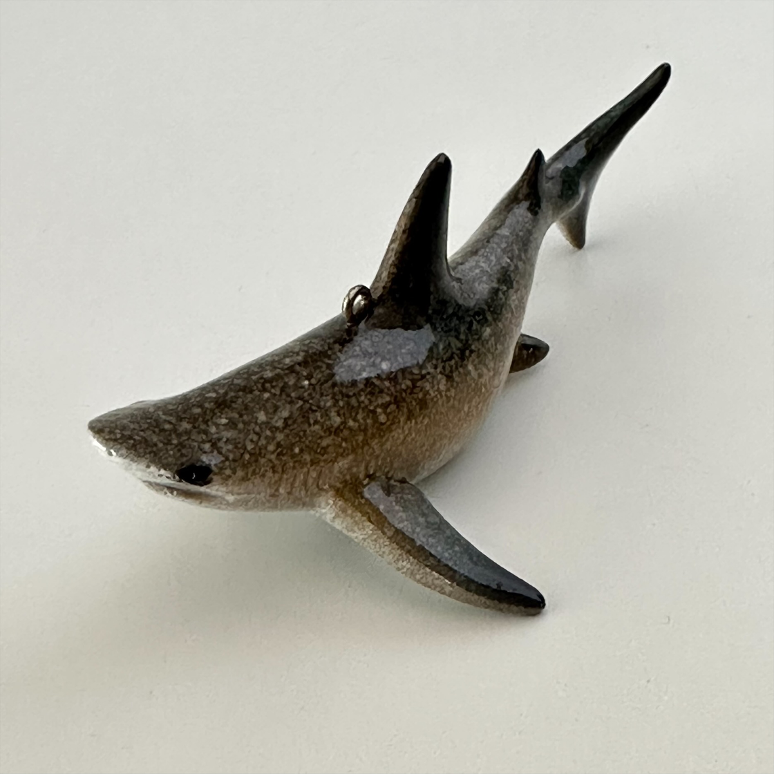 The rengöra shark ornament is a miniature replica of a real shark, featuring a lifelike appearance with vivid, shark-like coloring and a pair of striking eyes. It also includes a hook for easy hanging on your Christmas tree.