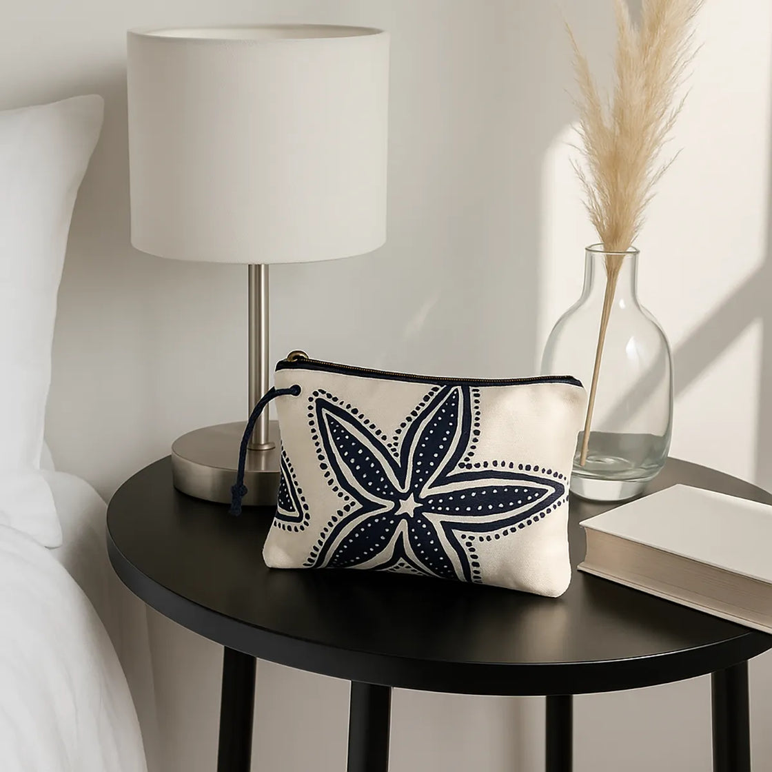 Rengöra nautical cosmetic pouch with navy blue starfish pattern on bedside table next to lamp