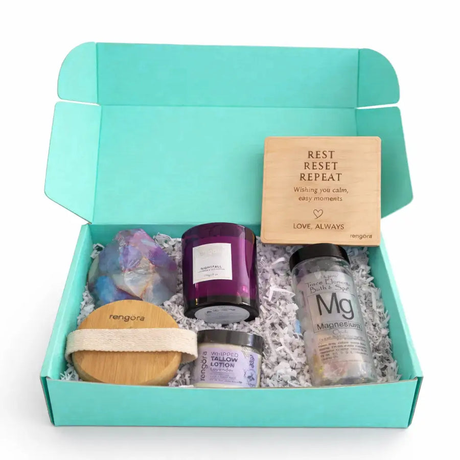 Gift set with candles, lotion, and a soap in a teal box on a white background