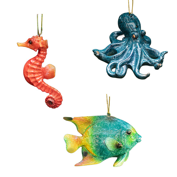 Decorative Christmas ornaments shaped like a seahorse, octopus, and fish on a white background