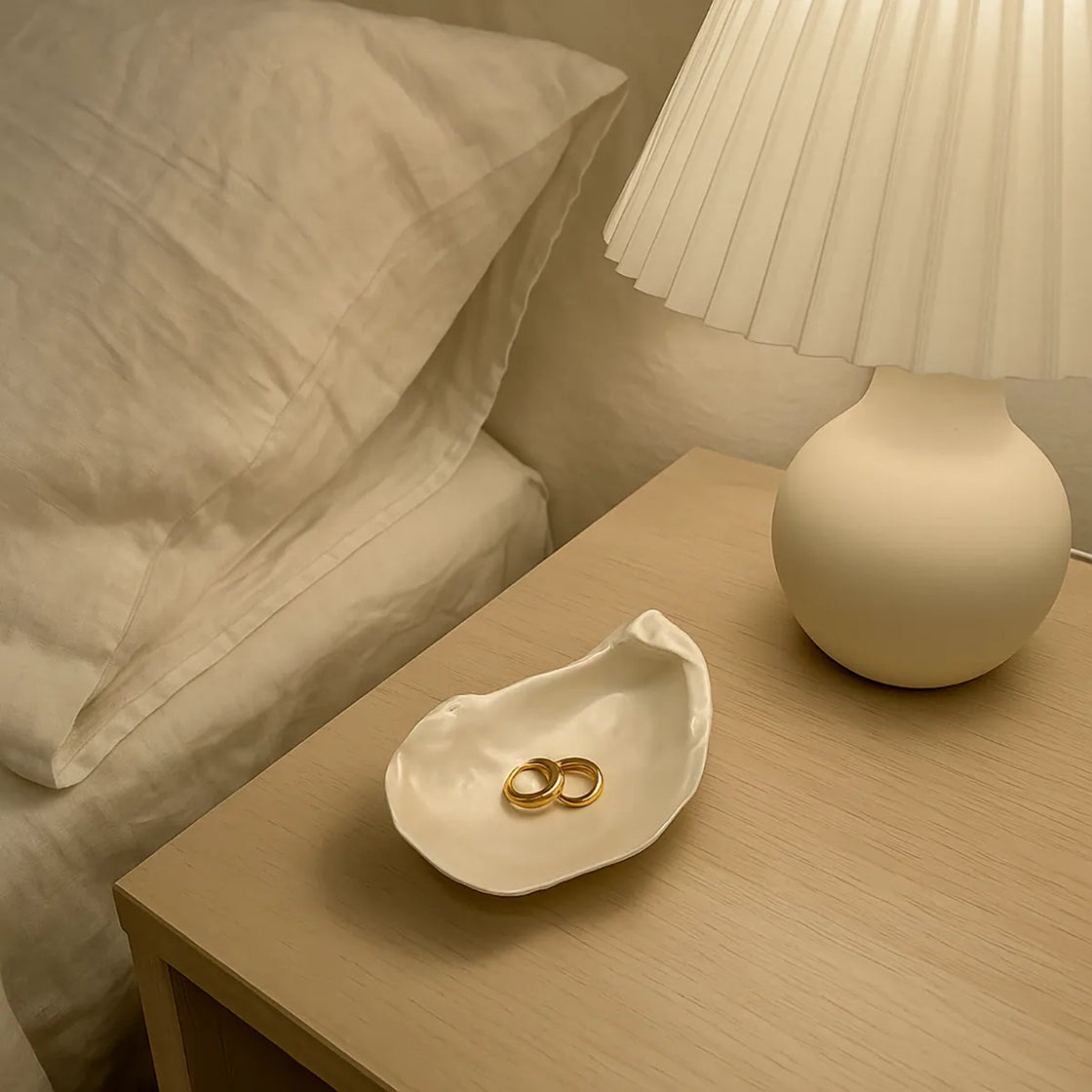 Rengöra ceramic oyster shell dish holding gold rings on bedside table beside lamp