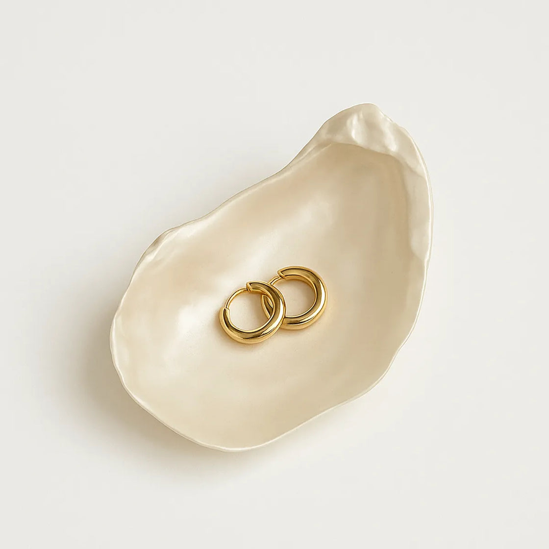 Rengöra ivory ceramic oyster shell dish with gold rings on white surface