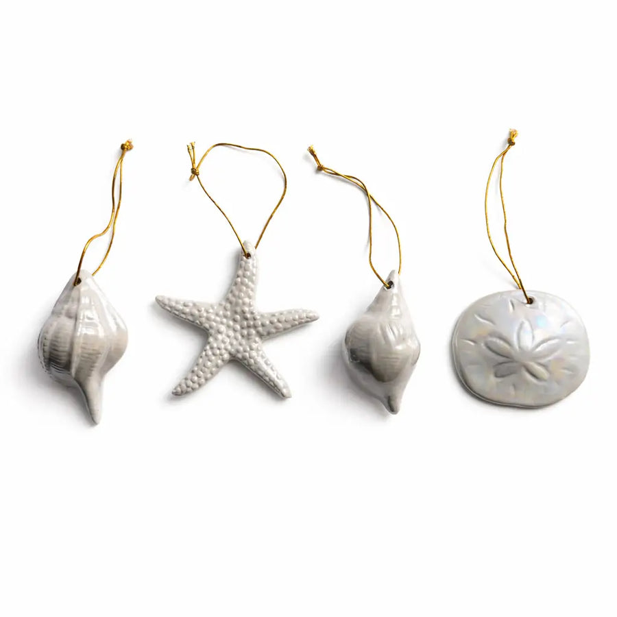 Set of four ceramic ornaments shaped like a shell, starfish, and two other designs on a white background.