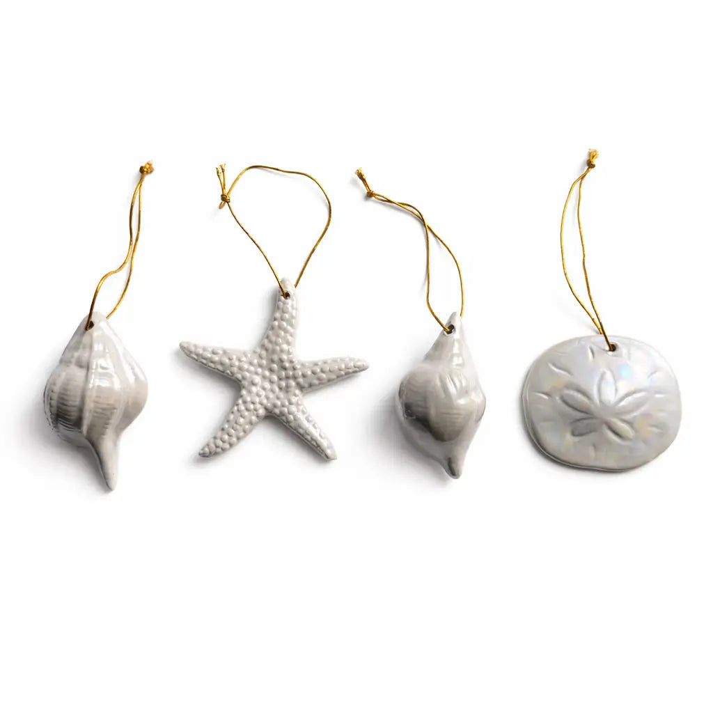 Set of four ceramic ornaments shaped like a shell, starfish, and two other designs on a white background.