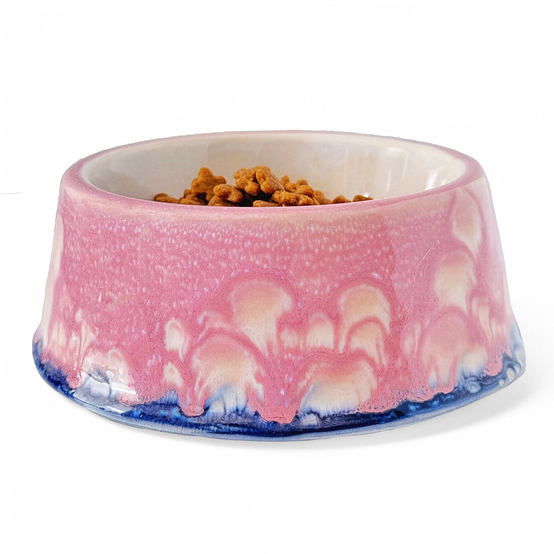 A standalone image of a handcrafted pink rengöra ceramic dog bowl with a detailed marbled glaze effect in pink, white, and blue, against a white background.