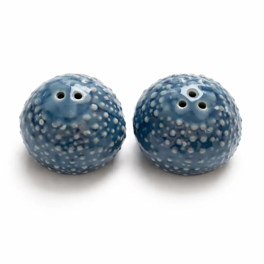 Two blue speckled salt and pepper shakers on a white background