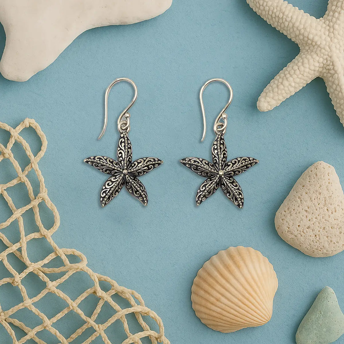 Starfish-shaped earrings on a blue background with starfish, shells, and a net.