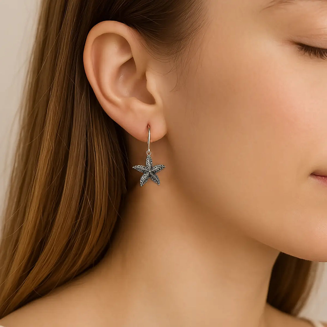 Starfish earring worn by a person with a neutral background