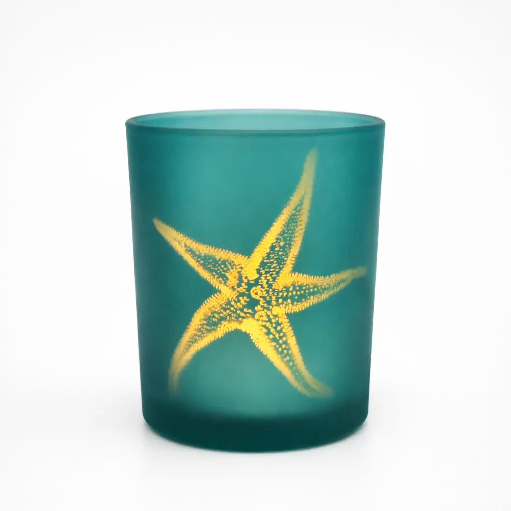 Green glass candle holder with a yellow starfish design on a white background
