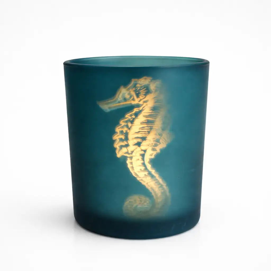 Teal candle holder with a gold seahorse design on a white background