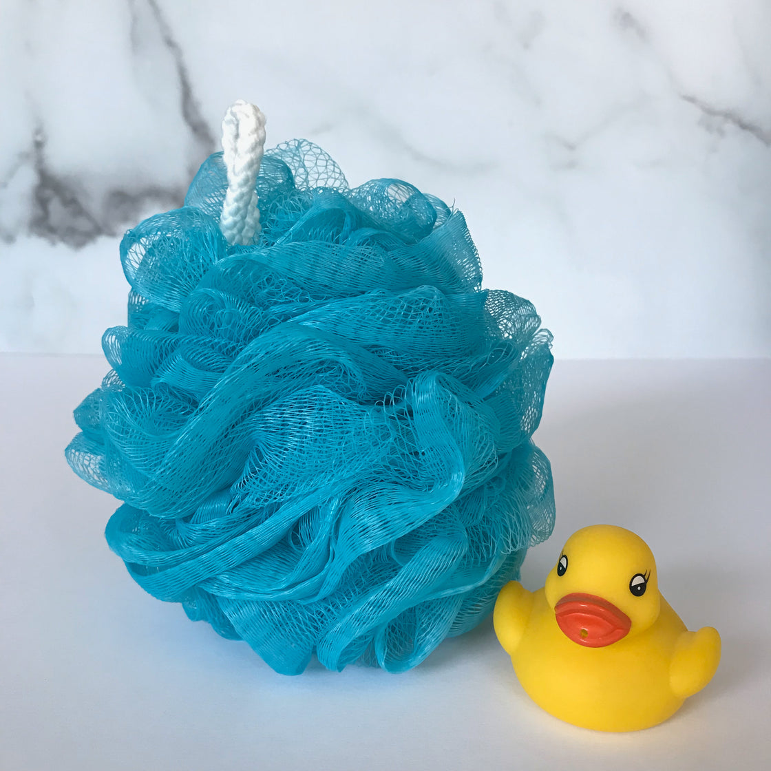 A turquoise rengora mesh scrubber accompanied by a yellow rubber duck, all set against a plain white background