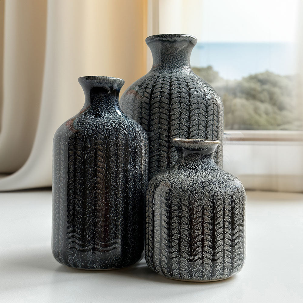 Three vases, positioned with elegance on the table by the window offering a view of the outside scenery