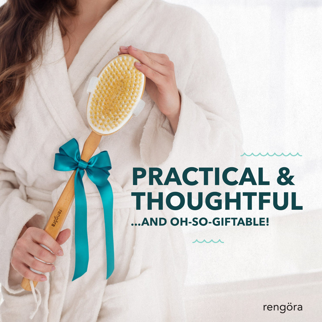 A woman in a plush white bathrobe holding a bamboo back brush wrapped with a teal bow, showcasing it as a thoughtful gift idea.