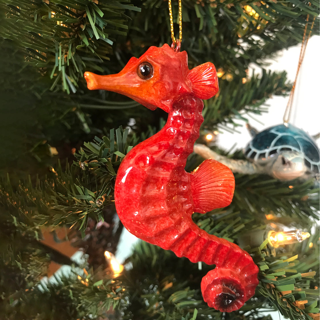 adorable hand-painted red seahorse ornament hanging on Christmas tree with lights