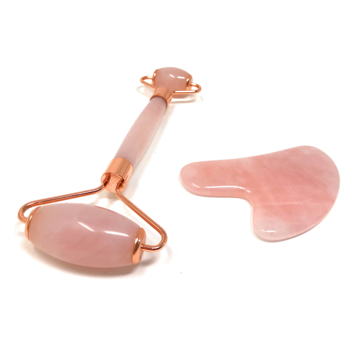 closeup of rose quartz roller and gua sha on white background