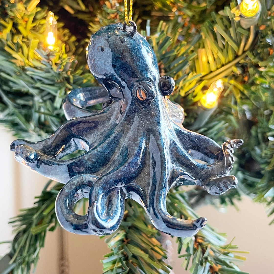 A detailed perspective of the rengora octopus displaying its glossy hand-painted turquoise blue hue as it dangles from a Christmas tree