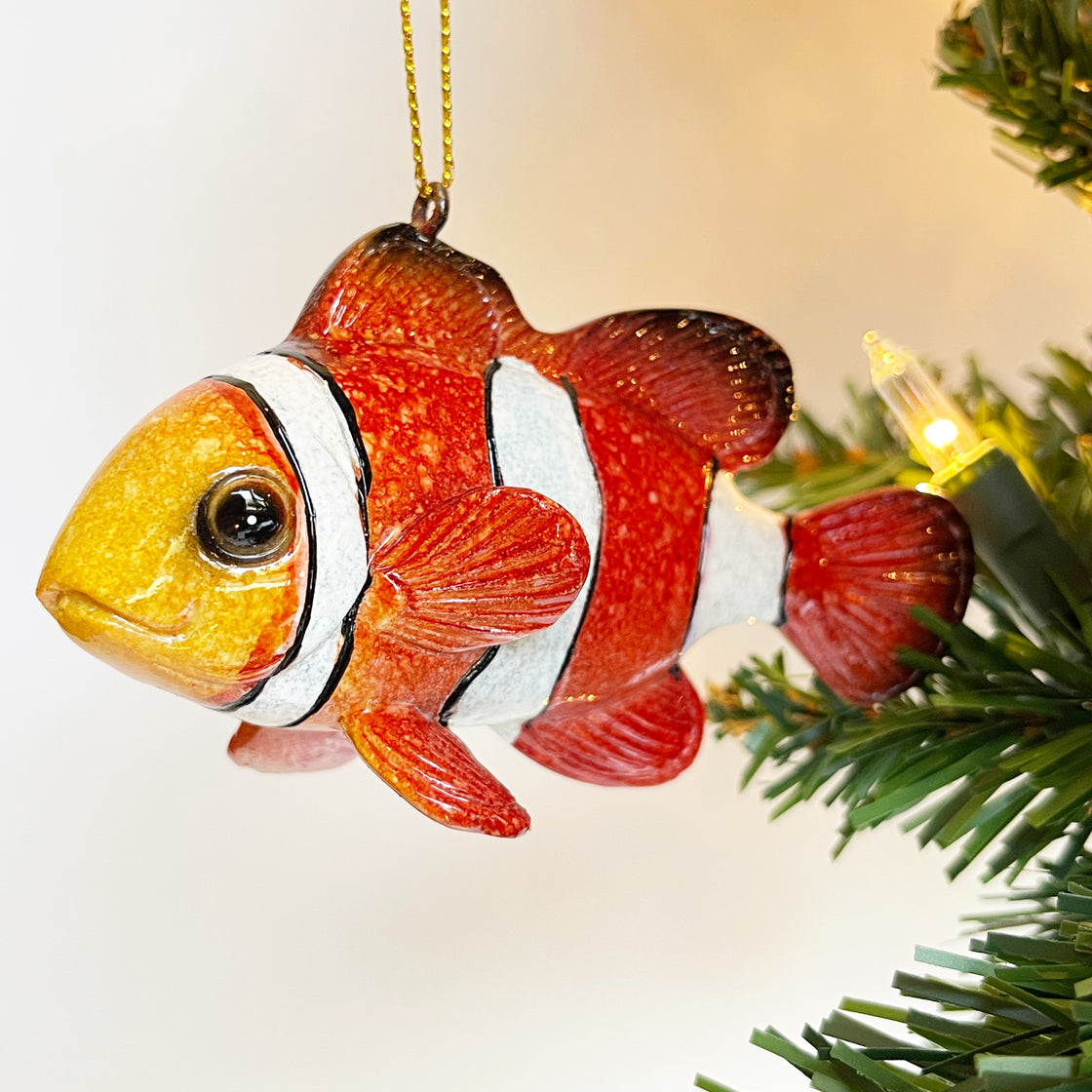 close-up view of rengöra tropical fish ornament with its vivid colors dangles elegantly from a Christmas tree branch adorned with Christmas light