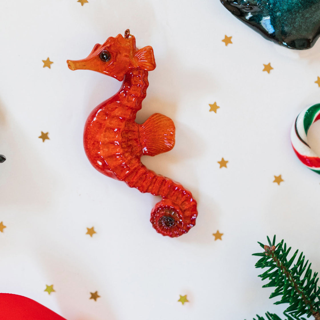 rengöra red seahorse ornament with sparkling star-shaped glitters set against a festive background featuring Christmas candy and stars