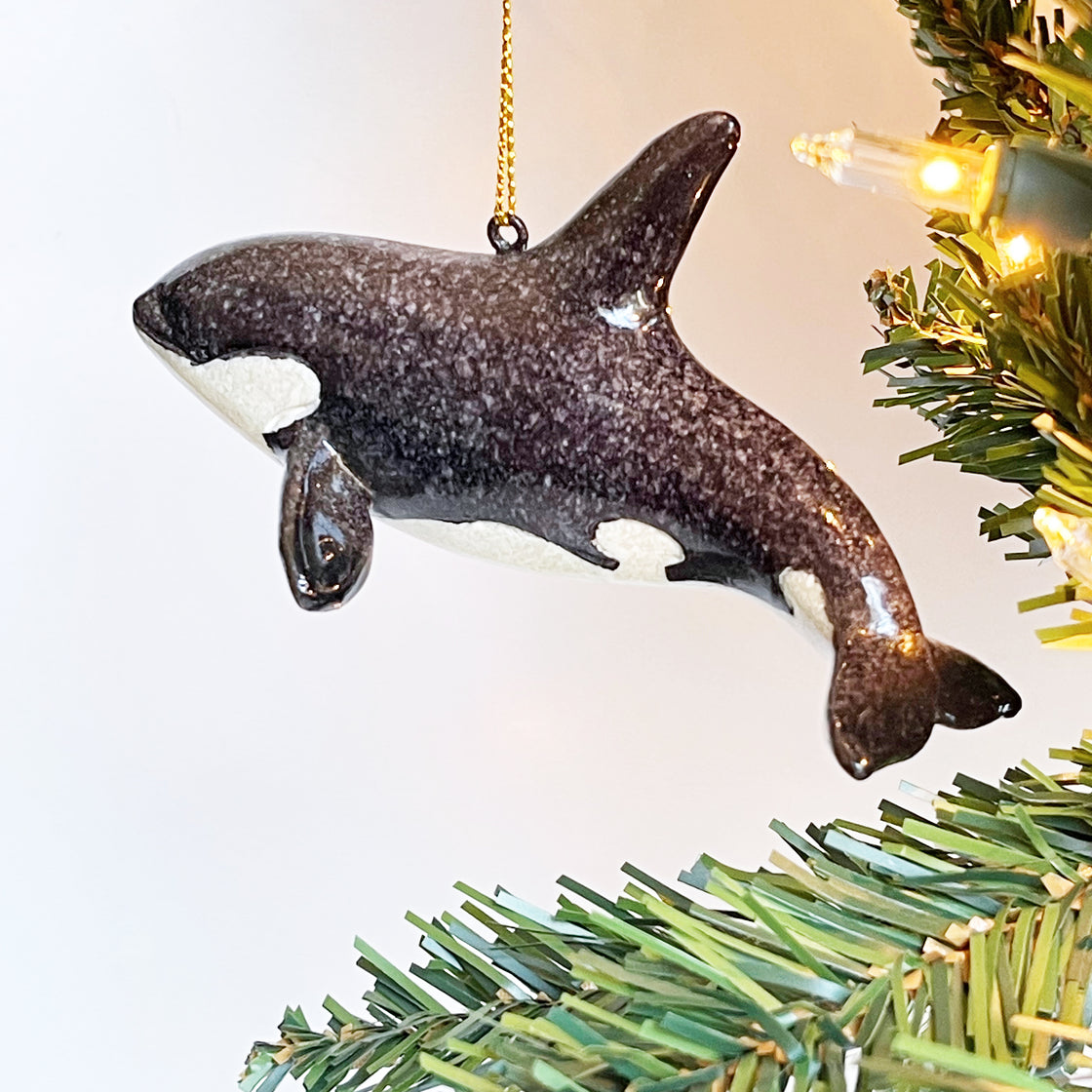 ornament featuring a hand-painted Orca Killer Whale hanging on a tree illuminated by Christmas light